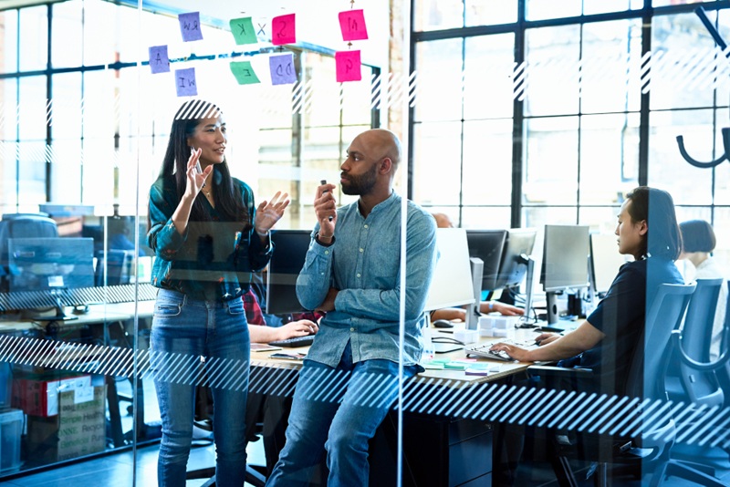two colleagues talking work in a spacious, modern, glass-fronted office